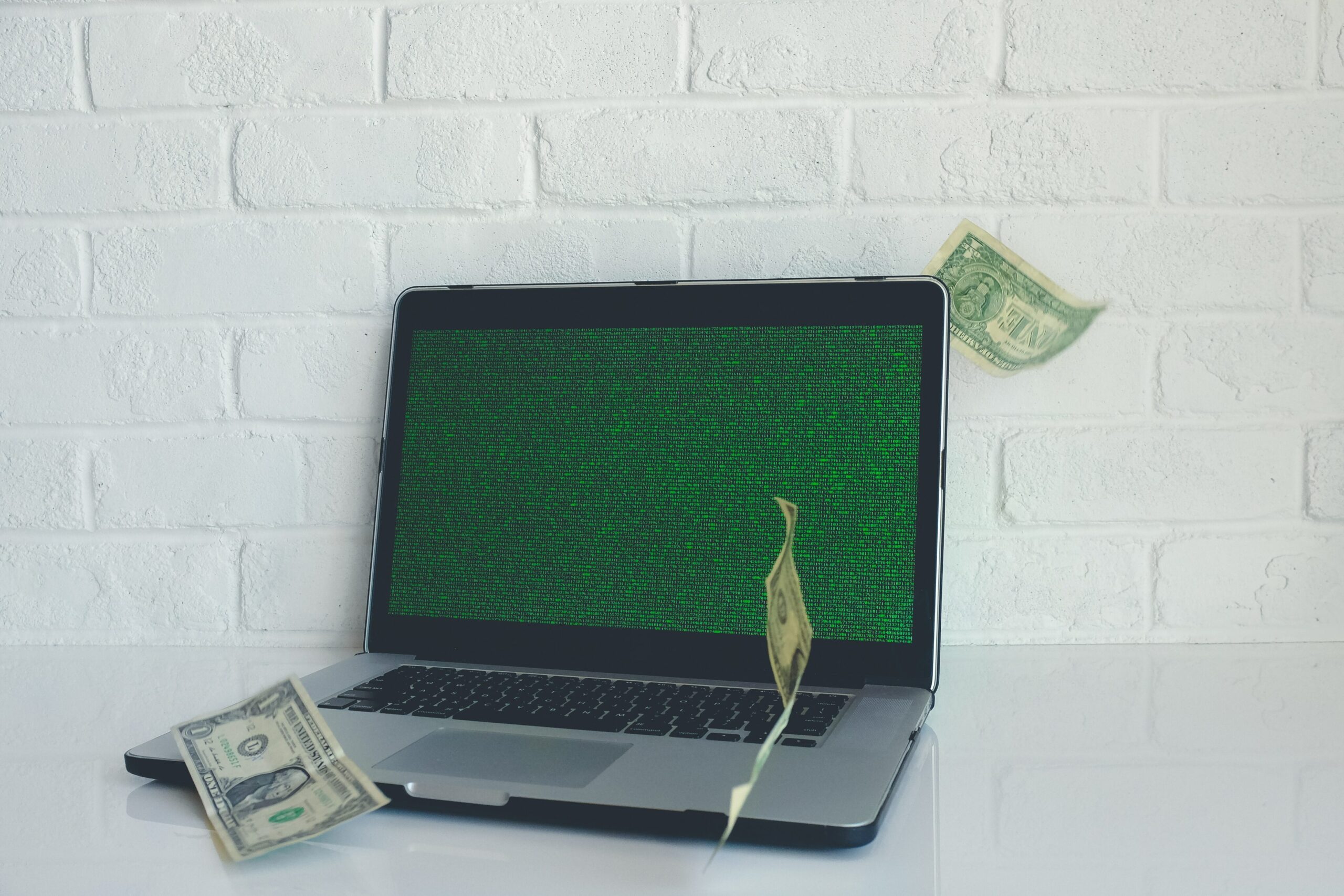 Un ordinateur avec 3 dollars en papier symbolise l'augmentation des profits suite à la consultation.